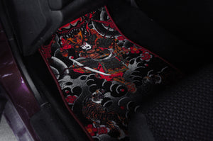 The "Samurai Tattoo Style!" floor mat by Incompletegl is a black car accessory situated in the footwell of your vehicle. It boasts an elaborate design inspired by Japanese culture, featuring a fierce samurai warrior wielding two swords, surrounded by swirling clouds and bright red accents, including a delicate floral pattern.