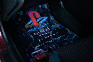 The Retro Playstation! floor mats by Incompletegl feature a colorful anime design with a retro-style PlayStation logo and bold red text reading "CHOOSE YOUR PLAYER," accompanied by smaller text that says "PRESS START BUTTON." These mats add a nostalgic gaming vibe to your vehicle’s interior.