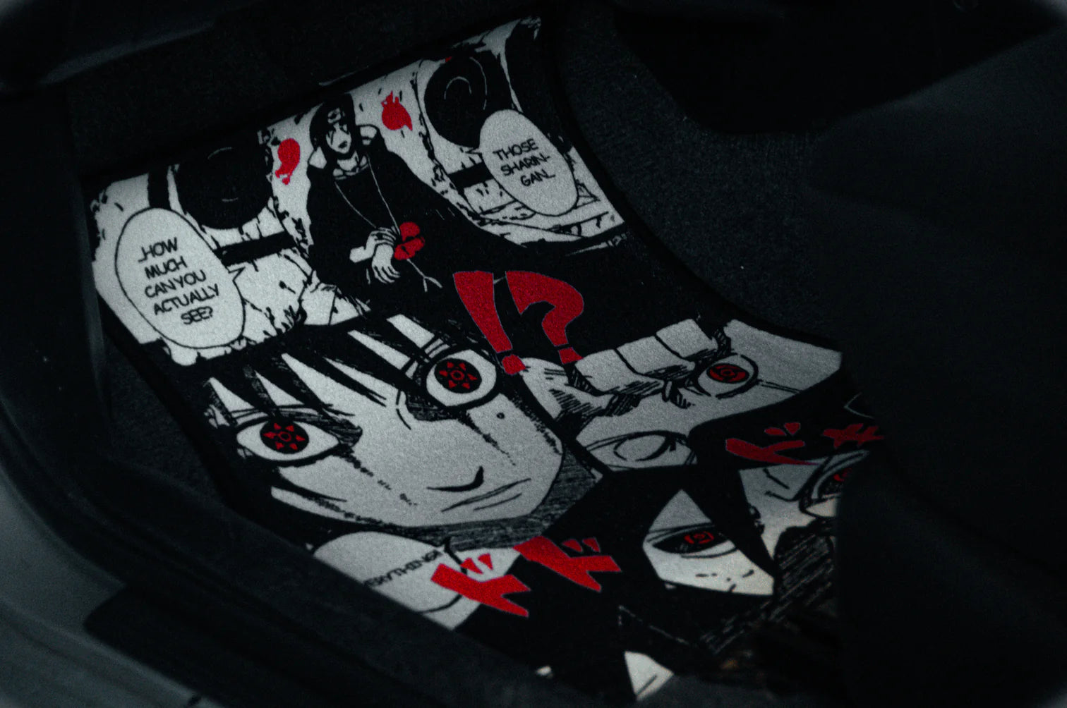 Close-up of an anime-themed car floor mat featuring black and white illustrations with red accents, reminiscent of the Naruto Mystery Pack! by Incompletegl. The design includes emotional expressions and speech bubbles, creating a dramatic effect.