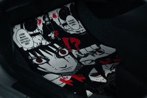 Close-up of an anime-themed car floor mat featuring black and white illustrations with red accents, reminiscent of the Naruto Mystery Pack! by Incompletegl. The design includes emotional expressions and speech bubbles, creating a dramatic effect.