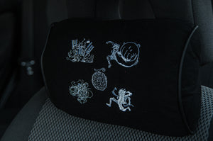 The Gear 5!!! Headrest Pillow by Incompletegl is a black car seat accessory inspired by Luffy's evolution. It boasts intricate white embroidery with abstract designs, capturing the adventurous spirit of One Piece and merging style with subtle flair.