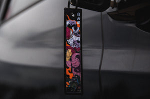 An "Incompletegl" DBZ x Ukiyo-e Style! Jet Tag featuring vibrant anime characters reminiscent of Dragon Ball Z hangs from a slightly reflective gray car door handle. The characters are depicted in various poses against backgrounds that blend shades of red, blue, purple, and orange.