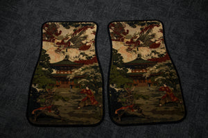 Two car floor mats from Incompletegl, called Ryujin x Raijin, 'The Palace Painting,' featuring intricate designs of a Japanese palace surrounded by trees and traditional buildings set against a gray background. The mats are placed side by side.