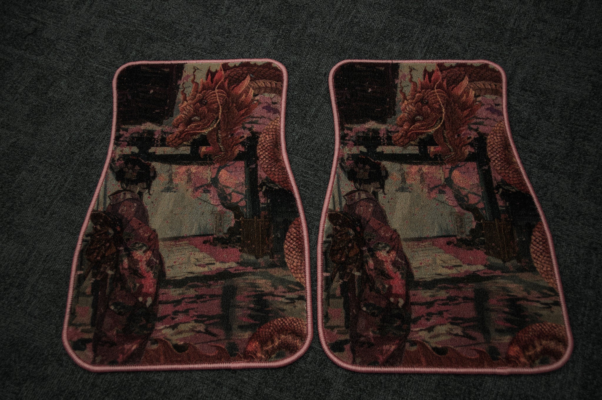 Two intricately patterned floor mats with pink borders, showcasing Japanese art with a mirrored design of an oriental dragon and a geisha against a scenic background. The Geisha x Dragon Familiar! floor mats by Incompletegl are placed side by side on a dark carpeted surface.