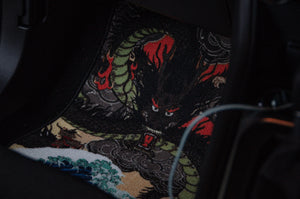 A car floor mat from Incompletegl's Dragon Ball Z x Ukiyo-e Style! collection, featuring an intricate, colorful design that depicts a fierce dragon with a red and green serpent-like body and a menacing face with red eyes, surrounded by flames, clouds, and waves. Reminiscent of Ukiyo-e art.