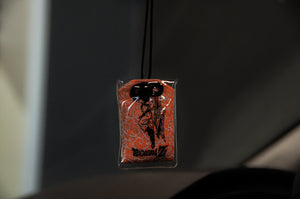 The Goku x Shenron | Omamori Charm by Incompletegl is a small rectangular air freshener that resembles an Omamori charm. It showcases Goku in his Super Saiyan form and hangs by a black string, with "DRAGON BALL Z" printed below the image. The background features an intricate orange pattern.