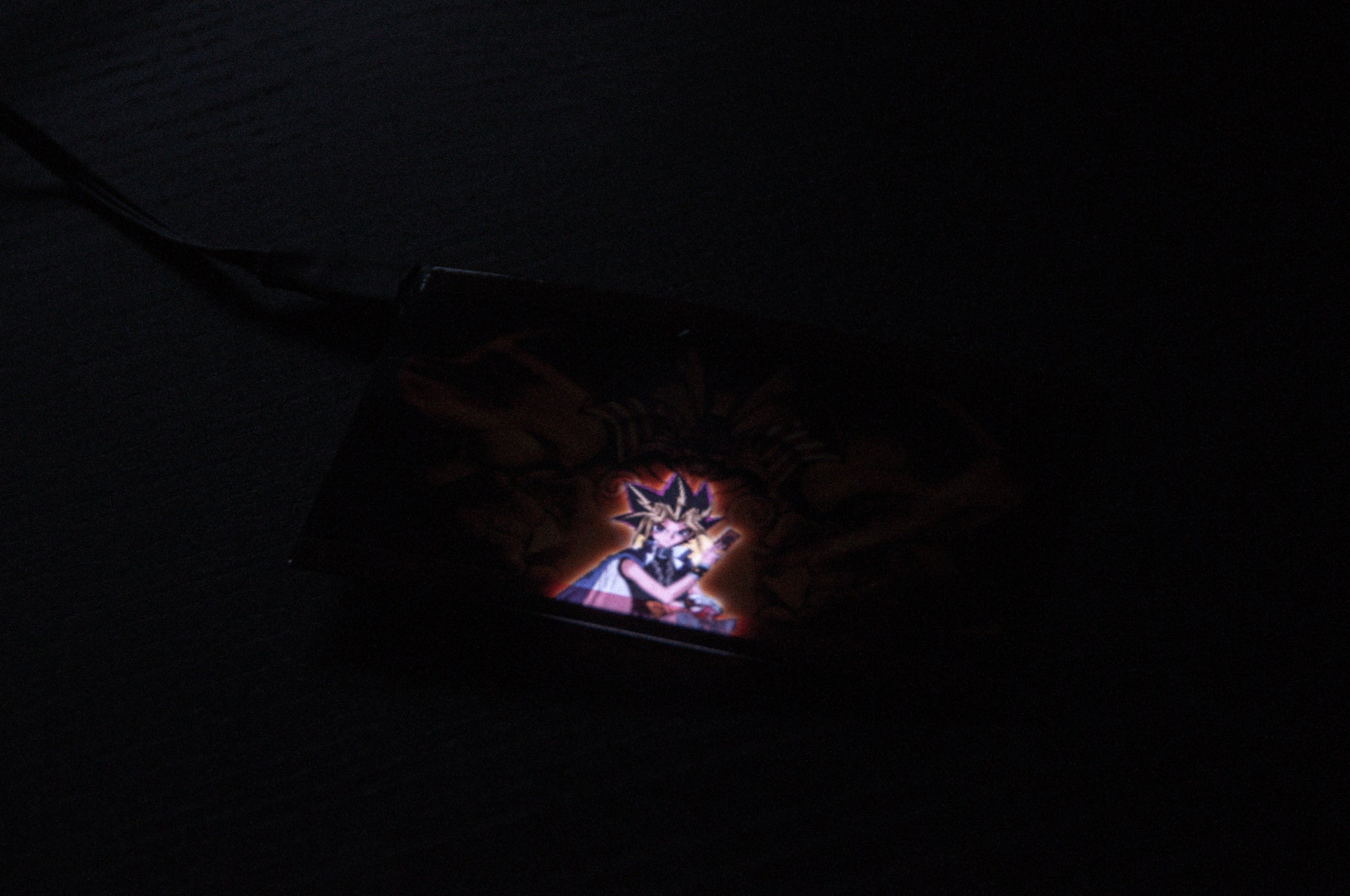 A dimly lit image showcases the Exodia! | Glow Panel by Incompletegl, featuring an anime-style character with spiky hair, reminiscent of the Yu-Gi-Oh! series, illuminated against a dark background. The panel is connected to a cable, giving it a distinct JDM accessory vibe.