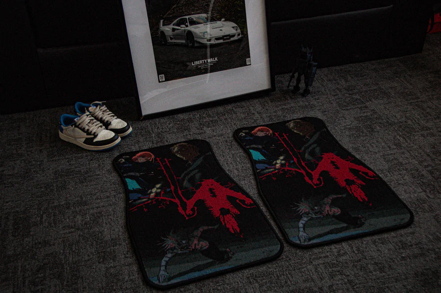 A pair of custom car mats with red graphics and a black and white framed car photo lay on the floor. Nearby, explore the Jujutsu Kaisen Mystery Pack by Incompletegl, featuring blue and white sneakers alongside a small black figurine, all set against the grey carpet.