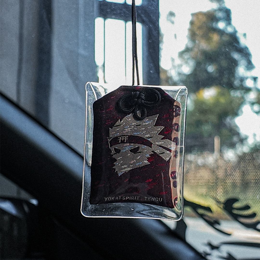 Tengu omamori charm hanging in a car – Incomplete