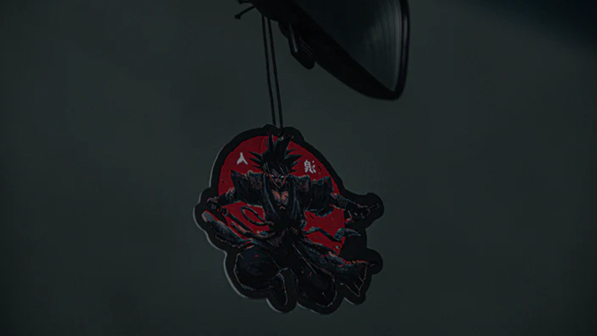 The Dragon Ball Z Super Pack! Bundle by Incompletegl includes a hanging car air freshener shaped like a warrior character in black armor with red accents. The dynamic warrior, holding a sword while crouching, is set against a red circular background. Perfect for fans of Dragon Ball Z, it easily attaches to the rearview mirror with a black string.