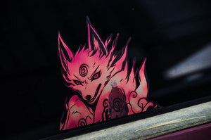 A dark surface displays a pink and black stylized fox decal with sharp features and swirling patterns, evoking an intense Naruto-themed vibe. A small figure stands before it, enhancing the drama of the fox's menacing expression. This scene is part of the Naruto Mystery Pack from Incompletegl’s Anime Bundle Pack.