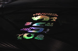 The Dragon Spine! | Holographic Decal by Incompletegl features a black surface adorned with a vibrant dragon decal, complete with Japanese characters and various motivational words in English such as "NO REGRETS, EVEN IN DEATH," "KAIZEN," and "IKIGAI." The design highlights a dragon spine, waves, and other symbolic imagery, perfectly enhancing your decal collection.